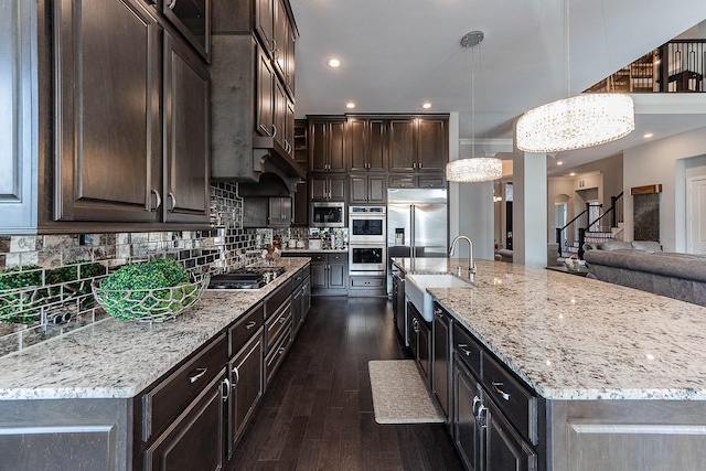 kitchen with light stone counters, dark brown cabinetry, decorative backsplash, built in appliances, and dark wood-style flooring