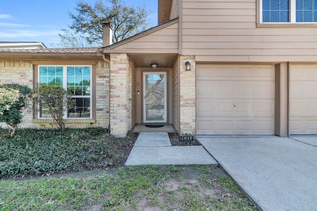 entrance to property featuring concrete driveway, a garage, and brick siding