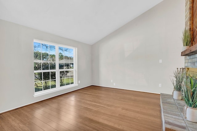 unfurnished living room featuring wood finished floors, a fireplace, and vaulted ceiling