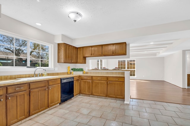 kitchen featuring light countertops, black dishwasher, brown cabinets, and a sink