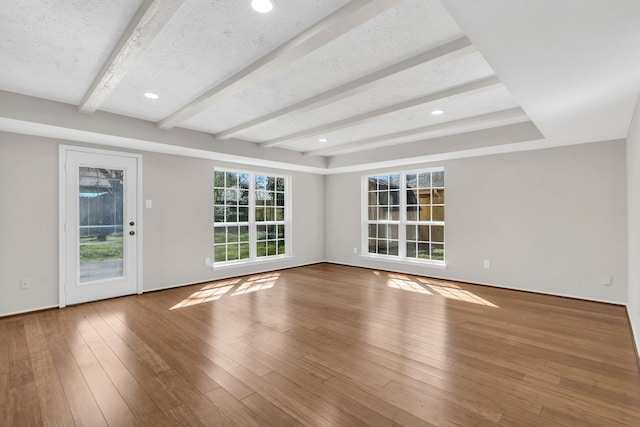 interior space with beam ceiling, wood finished floors, and a textured ceiling