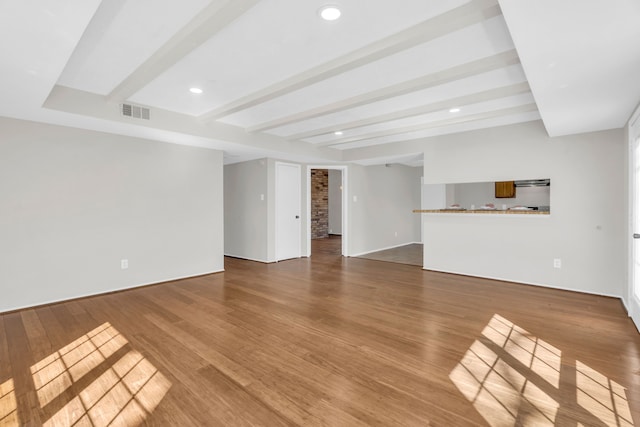 unfurnished living room with beam ceiling, recessed lighting, wood finished floors, and visible vents