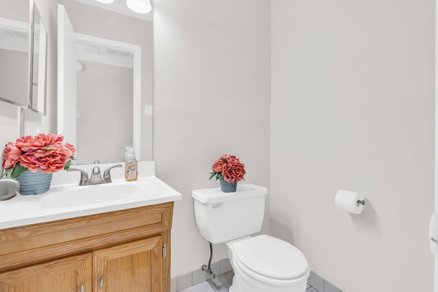 half bath with vanity, toilet, and baseboards