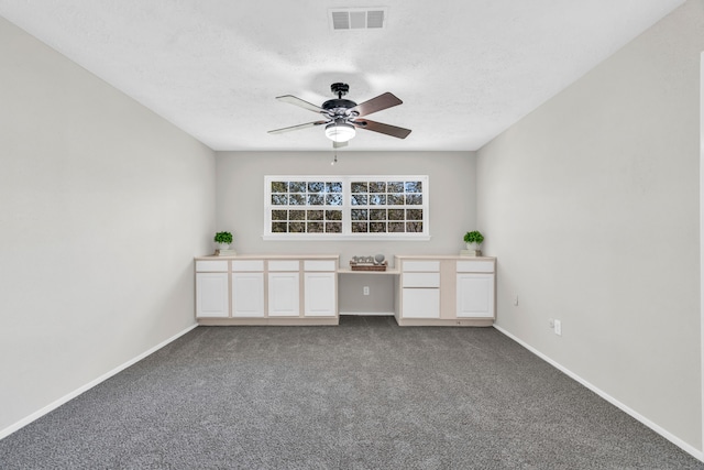 spare room with visible vents, baseboards, a ceiling fan, and dark colored carpet