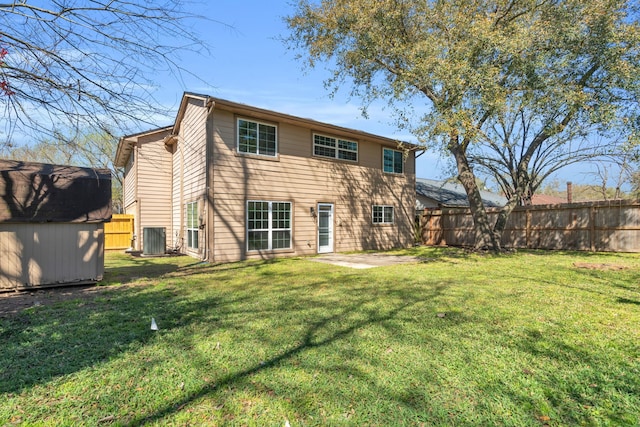 rear view of house with fence, central AC, a lawn, an outdoor structure, and a storage unit