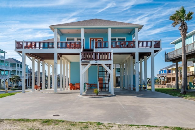 view of front facade featuring a carport, stairway, a porch, and roof with shingles