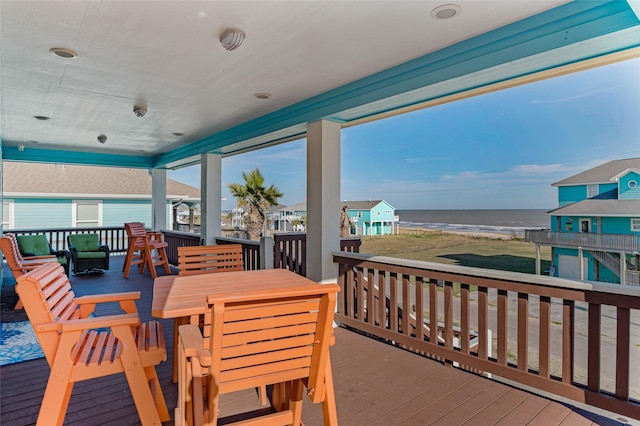 deck featuring outdoor dining space, a beach view, and a water view