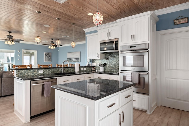 kitchen with open floor plan, appliances with stainless steel finishes, a peninsula, white cabinets, and a sink