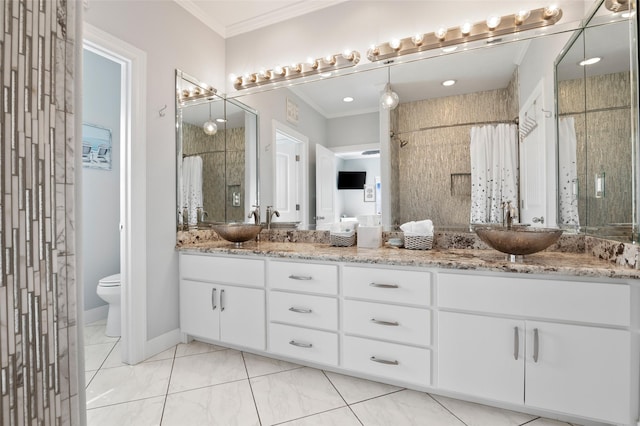 bathroom featuring crown molding, toilet, double vanity, a tile shower, and a sink