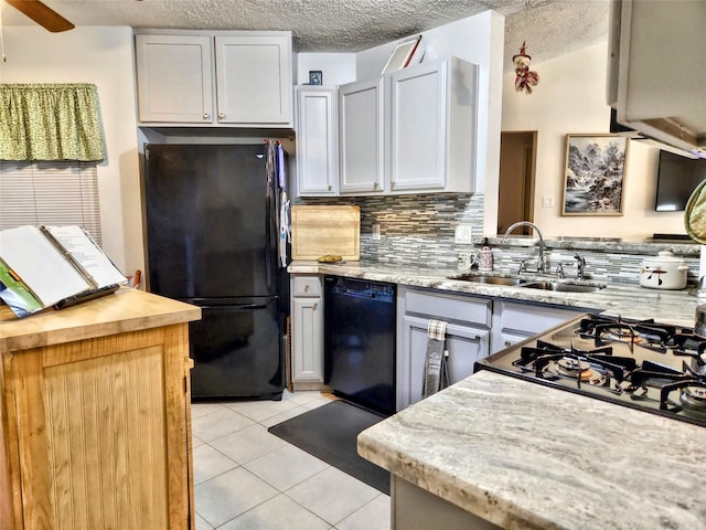 kitchen with light tile patterned floors, a sink, black appliances, a textured ceiling, and backsplash