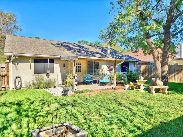 back of house featuring fence, a lawn, and stucco siding