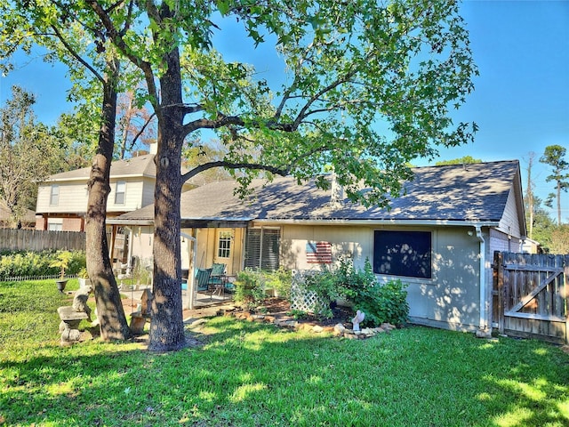 rear view of property with a patio, a shingled roof, a yard, and fence