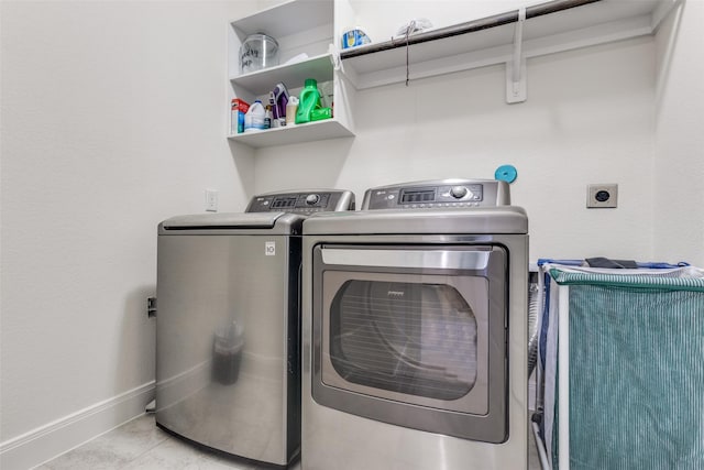 laundry room with tile patterned flooring, baseboards, laundry area, and washer and clothes dryer