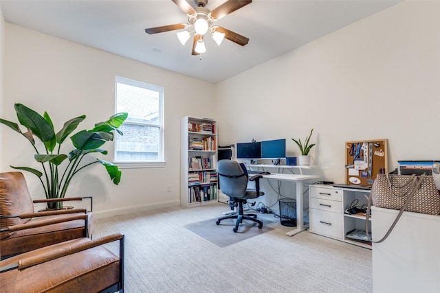 office space featuring light carpet, baseboards, and ceiling fan