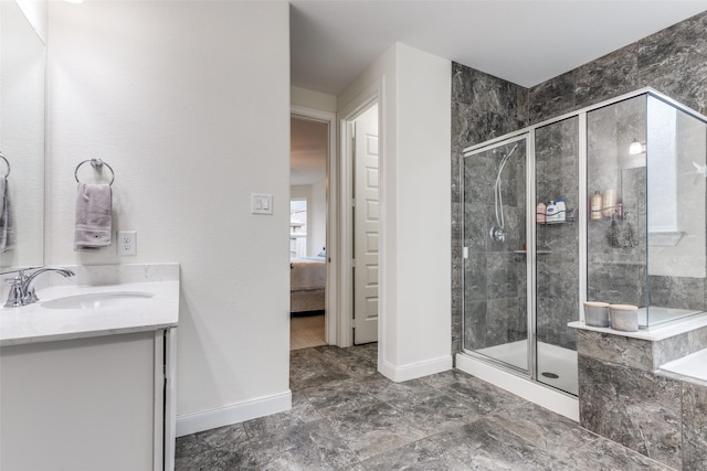 ensuite bathroom with vanity, baseboards, a stall shower, and ensuite bathroom