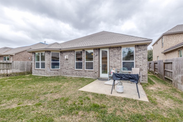 rear view of house featuring a yard, a patio, brick siding, and a fenced backyard