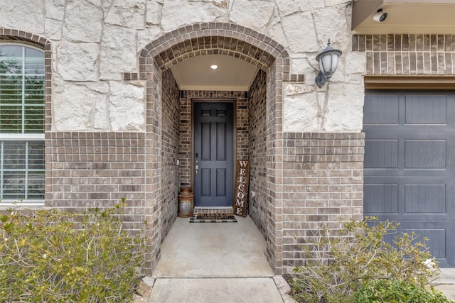 doorway to property featuring brick siding and a garage