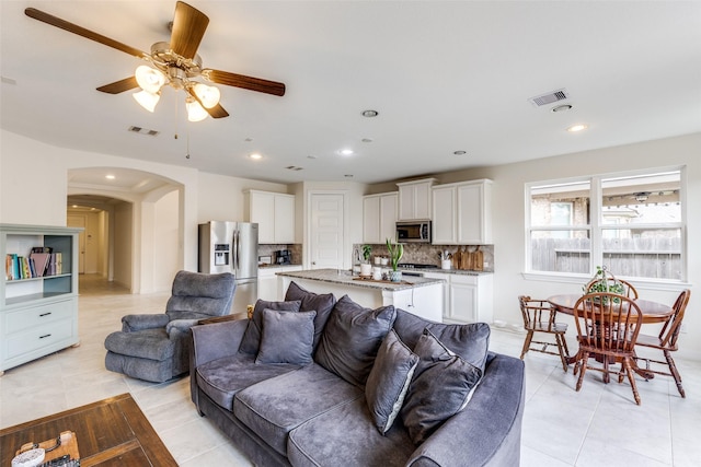 living area with arched walkways, visible vents, recessed lighting, and light tile patterned floors