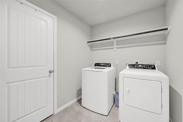 laundry room featuring light tile patterned floors, baseboards, laundry area, and washing machine and clothes dryer