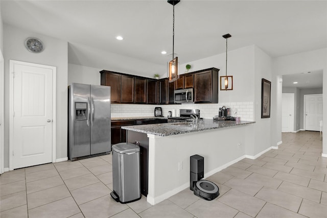 kitchen featuring dark brown cabinets, decorative backsplash, a peninsula, stone countertops, and stainless steel appliances