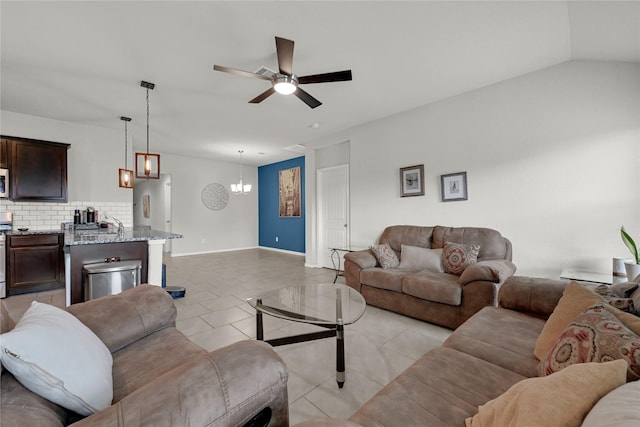 living room featuring baseboards, light tile patterned flooring, and ceiling fan with notable chandelier