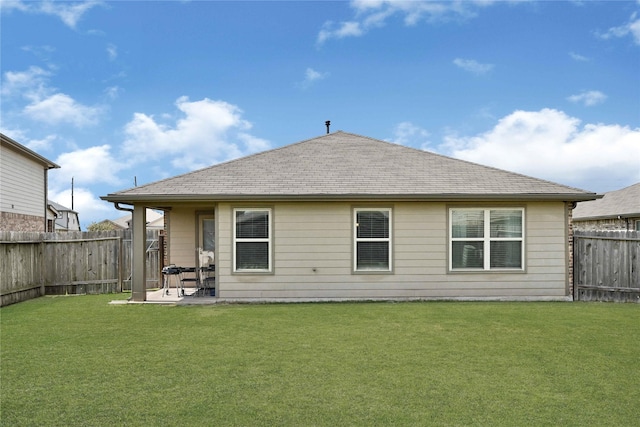 rear view of property featuring a patio area, a lawn, a fenced backyard, and a shingled roof