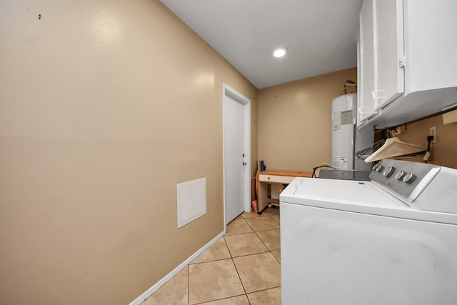 washroom with baseboards, water heater, light tile patterned floors, cabinet space, and separate washer and dryer