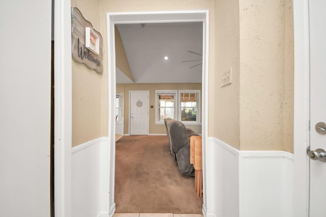 corridor with wainscoting, carpet, and a textured wall