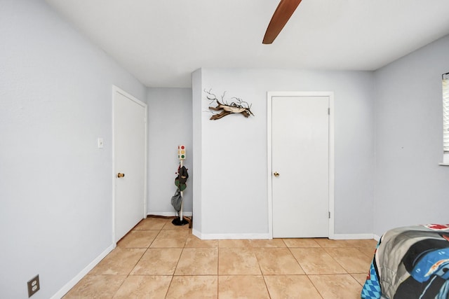 bedroom featuring baseboards, light tile patterned flooring, and a ceiling fan