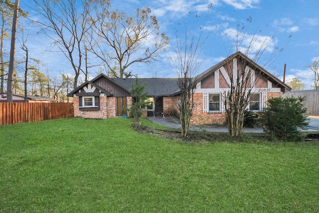 view of front of house with a front lawn, fence, brick siding, and a patio area