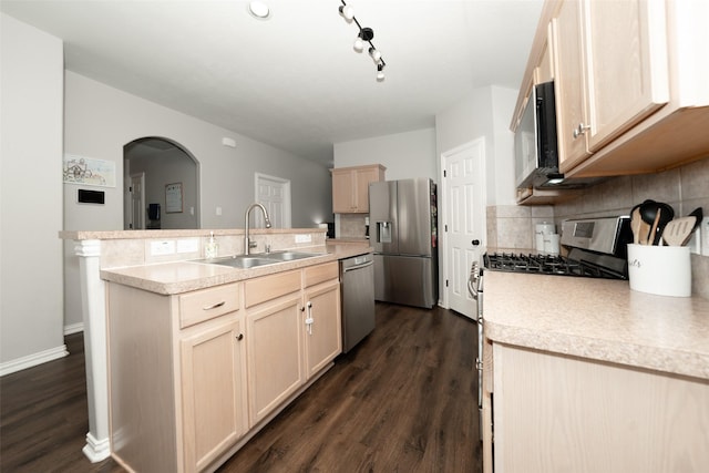 kitchen with a center island with sink, a sink, tasteful backsplash, stainless steel appliances, and light countertops