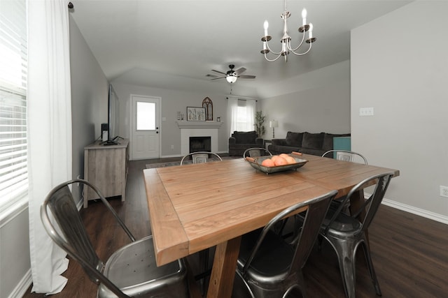 dining area with baseboards, dark wood finished floors, a fireplace, and ceiling fan with notable chandelier