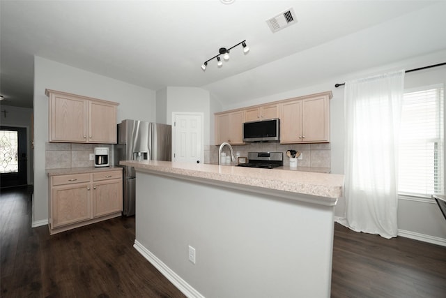 kitchen with light brown cabinetry, appliances with stainless steel finishes, light countertops, and lofted ceiling