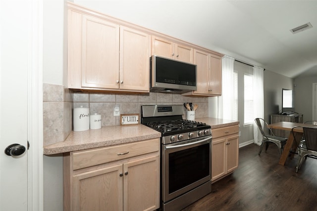 kitchen with light brown cabinetry, dark wood-type flooring, light countertops, appliances with stainless steel finishes, and tasteful backsplash