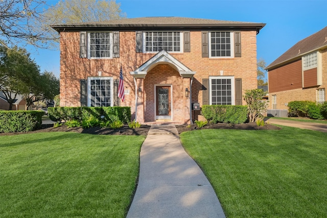 colonial house with a front yard and brick siding