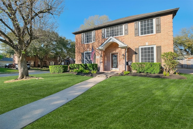 colonial house featuring brick siding and a front yard