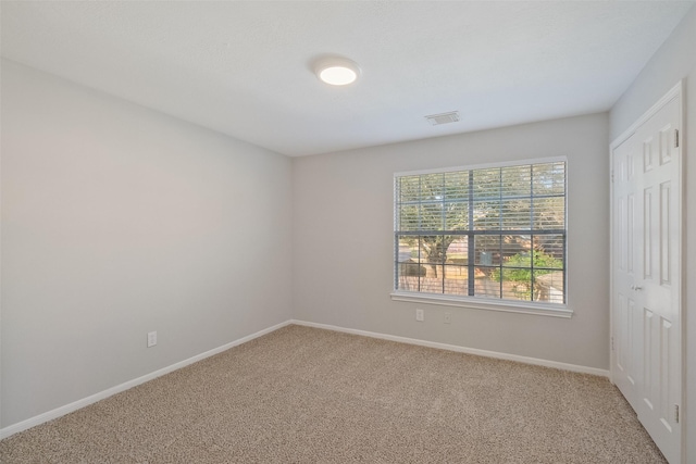 carpeted spare room with visible vents and baseboards