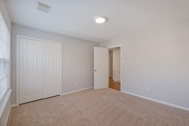 unfurnished bedroom featuring a closet, baseboards, visible vents, and carpet floors