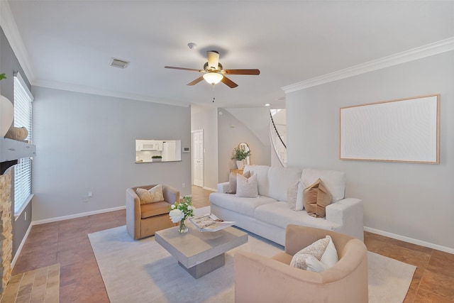 living room featuring ornamental molding, a ceiling fan, a stone fireplace, light tile patterned floors, and baseboards