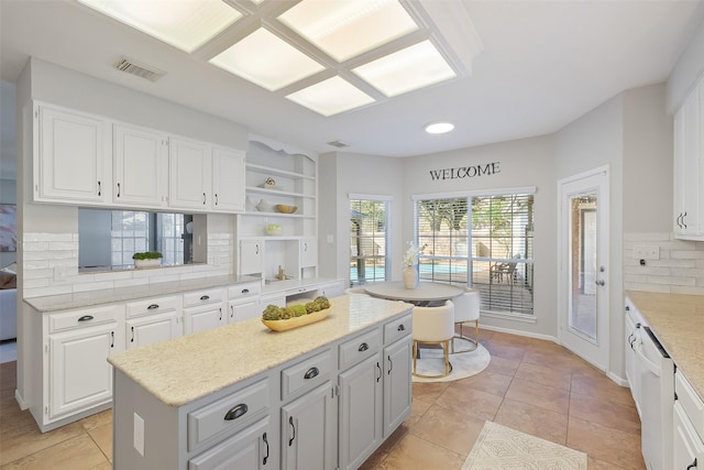 kitchen with visible vents, open shelves, a kitchen island, backsplash, and white cabinetry