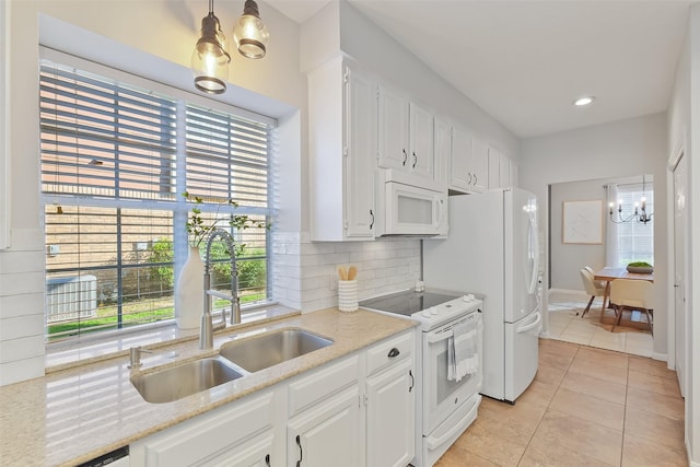 kitchen with a notable chandelier, a sink, white appliances, light tile patterned floors, and decorative backsplash