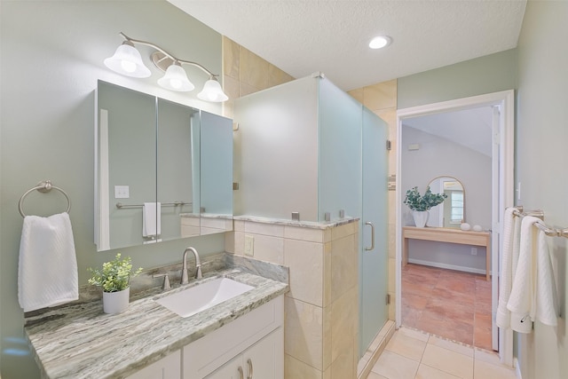 full bath featuring tile patterned floors, a textured ceiling, a stall shower, and vanity