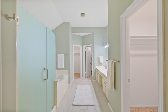 full bath with a walk in closet, visible vents, tile patterned flooring, a bath, and vanity