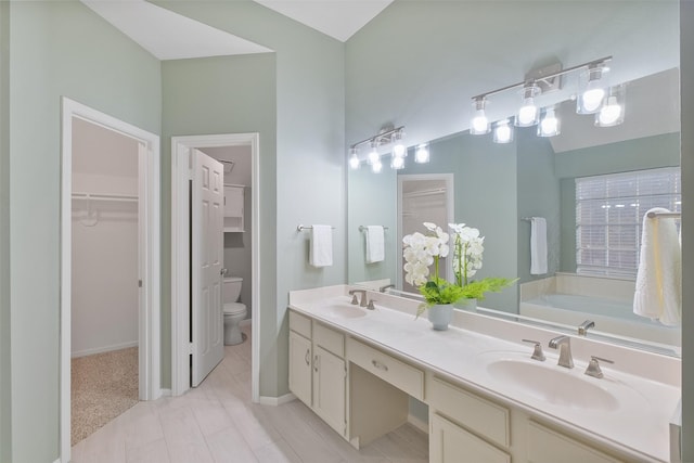 full bath with a walk in closet, double vanity, toilet, and a sink