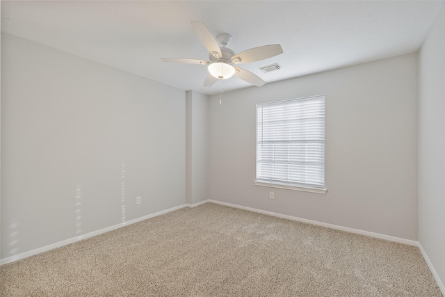 carpeted spare room with visible vents, baseboards, and ceiling fan