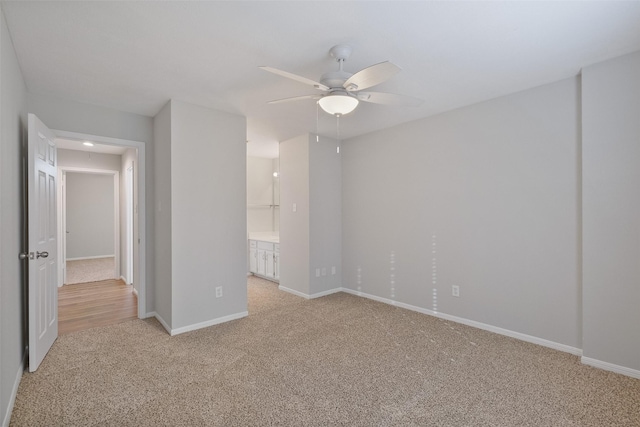 unfurnished bedroom with light colored carpet, ensuite bath, baseboards, and a ceiling fan