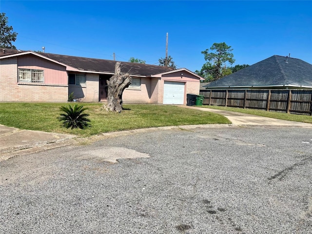 view of front facade with fence, an attached garage, concrete driveway, a front lawn, and brick siding