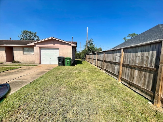 view of yard with fence, a garage, and driveway