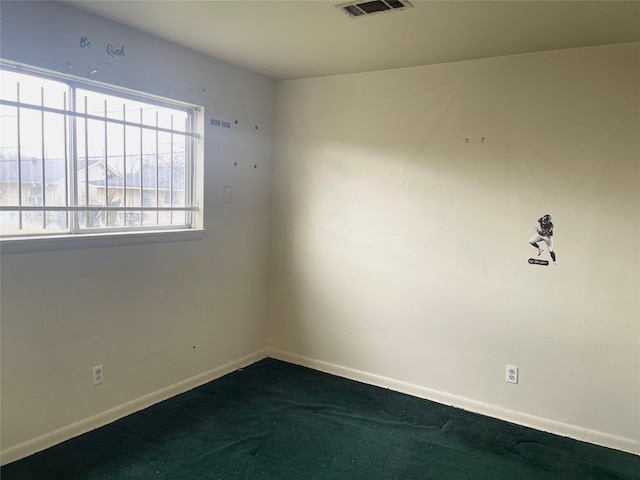 unfurnished room with visible vents, baseboards, and dark colored carpet