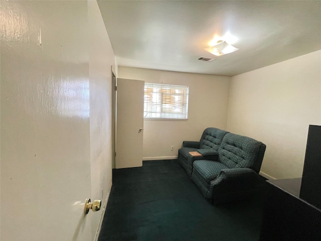 living area with visible vents, dark carpet, and baseboards